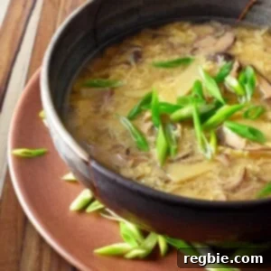 A closeup of paleo hot and sour soup in a bowl ready to be served, showcasing its rich texture and colors.