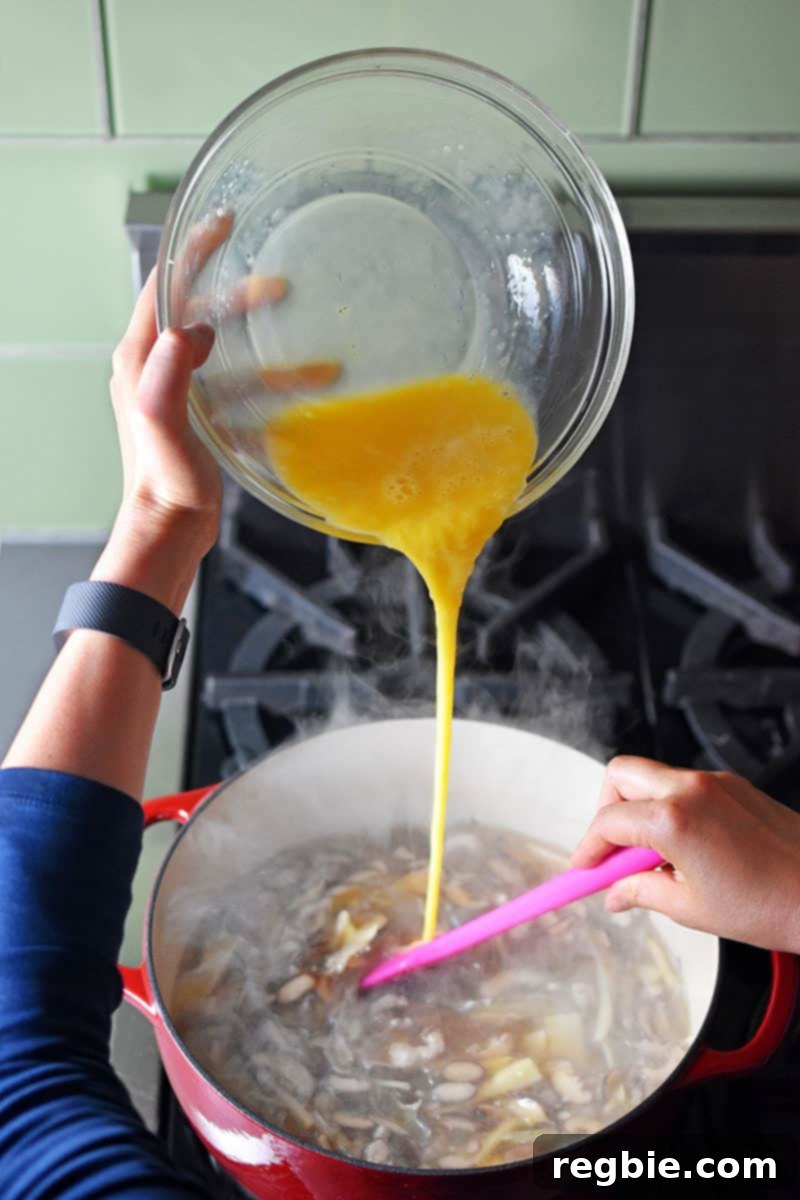 Zesty Whole30 Gluten Free Hot and Sour Soup 10 Slowly pouring whisked eggs into the steaming pot of Hot and Sour Soup, creating beautiful egg ribbons.