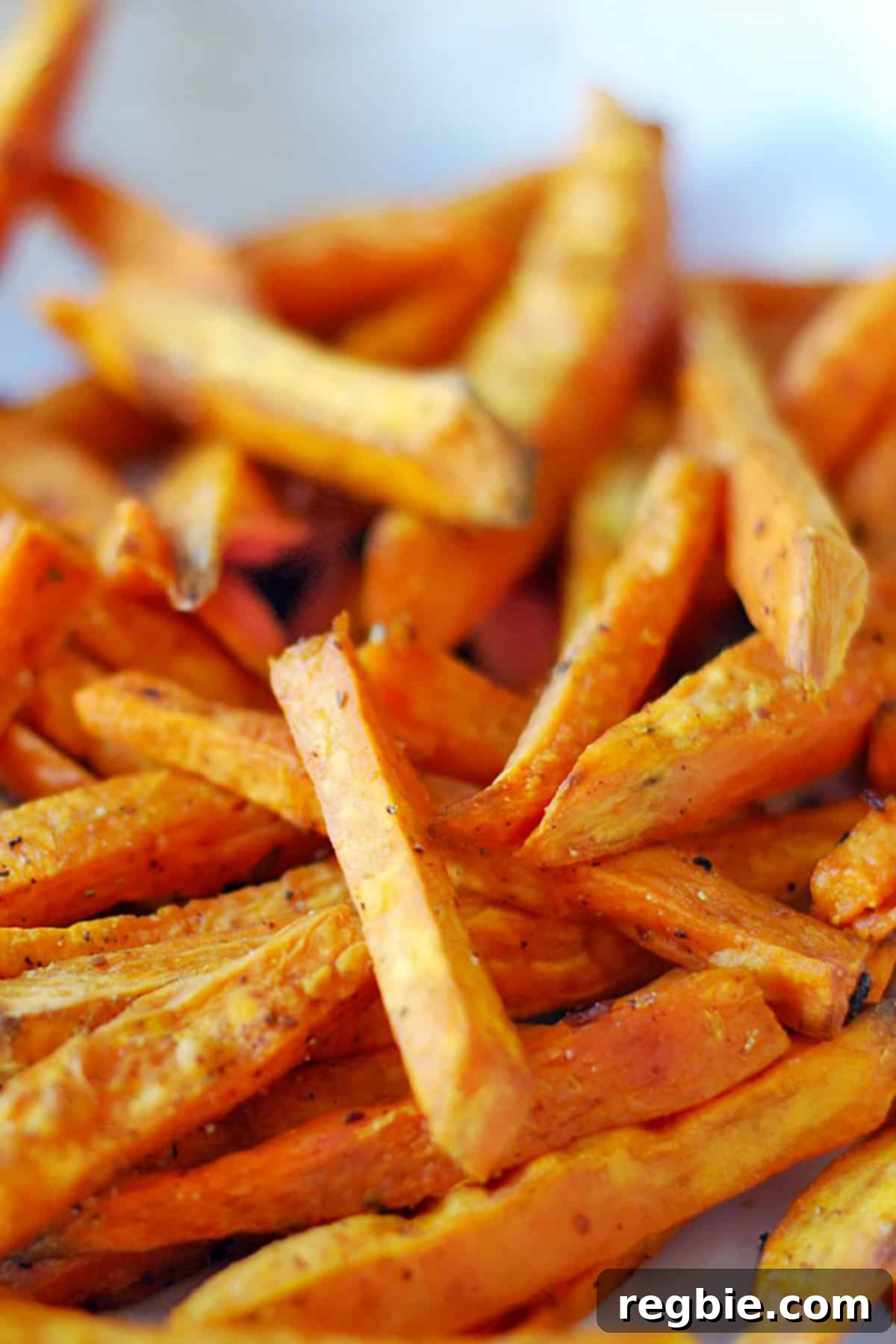 A close-up portrait of oven-baked or air fryer cooked sweet potato fries, perfectly golden and seasoned.