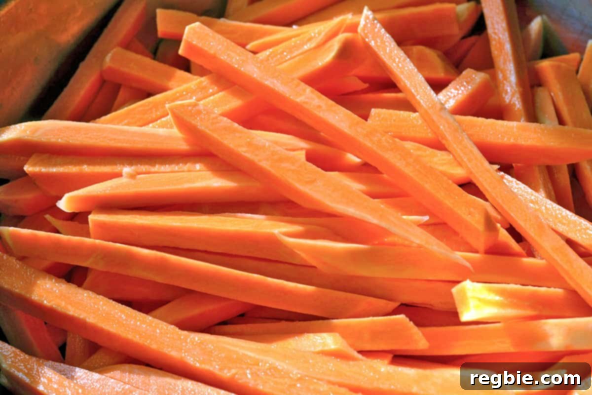 Sweet potatoes meticulously cut into uniform matchsticks, arranged neatly on a cutting board.