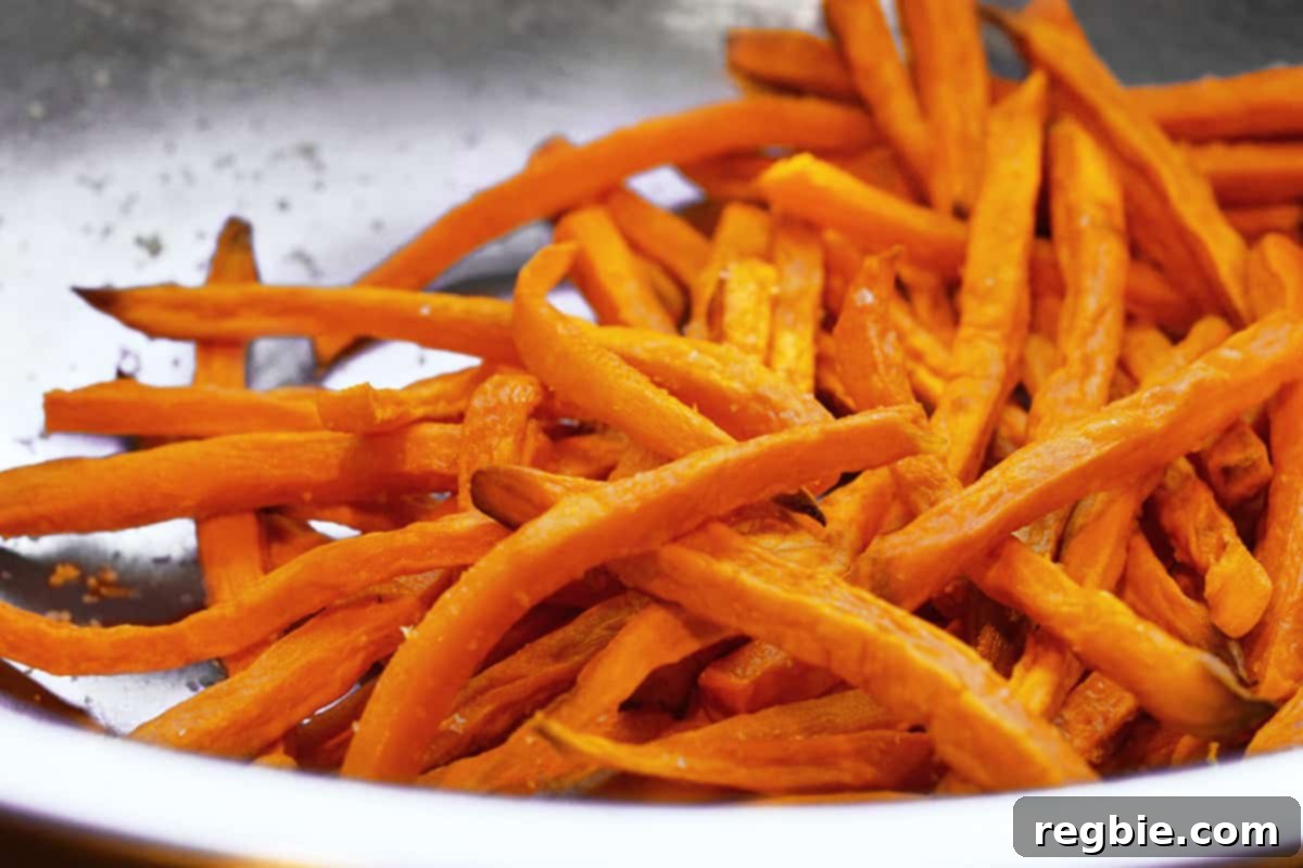 A silver bowl brimming with crispy, golden air-fried sweet potato fries, perfectly seasoned.