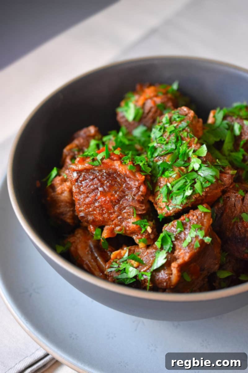 An overhead shot of a bowl of Instant Pot Magic Short Ribs in a dark blue bowl ready to serve, garnished with fresh parsley.