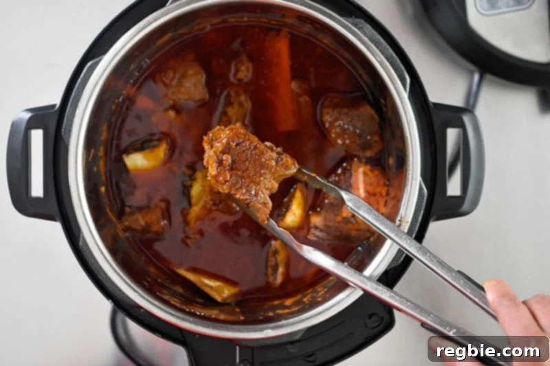 An overhead shot of Instant Pot Magic Short Ribs finished cooking in an Instant Pot, with the lid just removed, showing the tender ribs in rich sauce.
