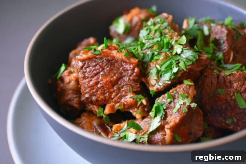A side view closeup of a bowl of Instant Pot Magic Short Ribs, showcasing the tender meat and rich sauce.