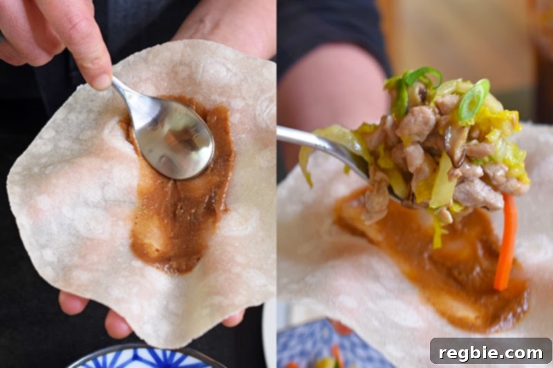 Using the back of a spoon to spread Paleo Hoisin Sauce on a grain-free tortilla before adding the Paleo Moo Shu Pork.