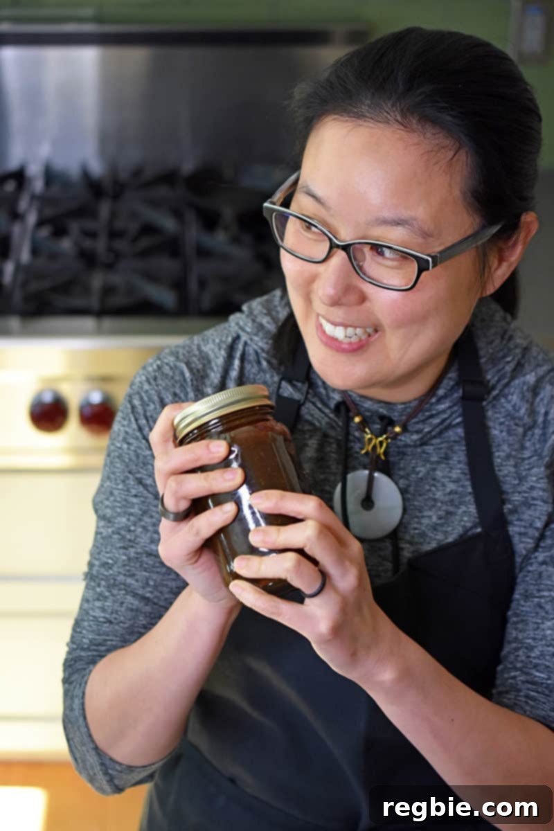 A shot of a smiling woman shaking a jar of All-Purpose Stir-Fry Sauce, preparing it for the stew.