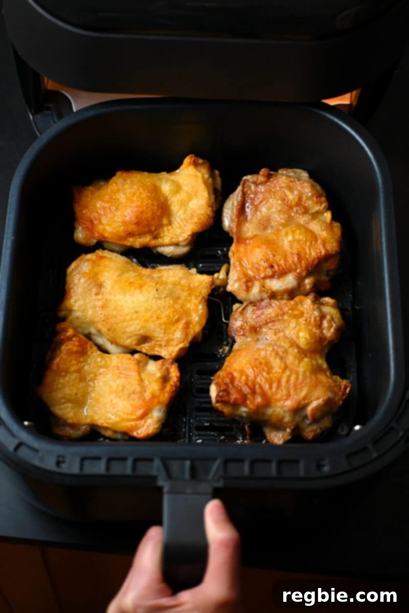 Ultimate Crispy Air Fryer Chicken Thighs 2 An overhead shot of golden-brown crispy air fryer chicken thighs perfectly cooked in an open air fryer basket.
