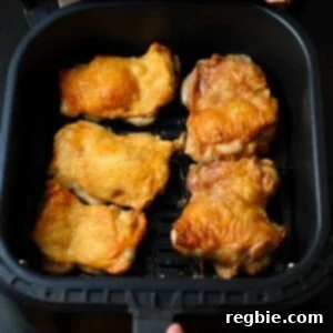 An overhead shot of crispy air fryer chicken thighs in an open air fryer basket.