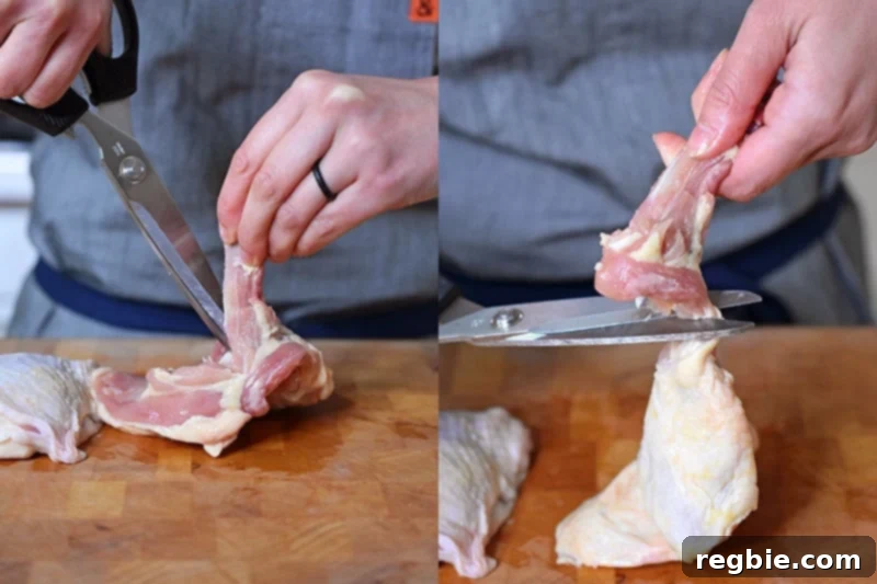 Ultimate Crispy Air Fryer Chicken Thighs 5 A person is expertly removing the bone from a skin-on chicken thigh using a pair of kitchen shears, showing a clean deboning technique.
