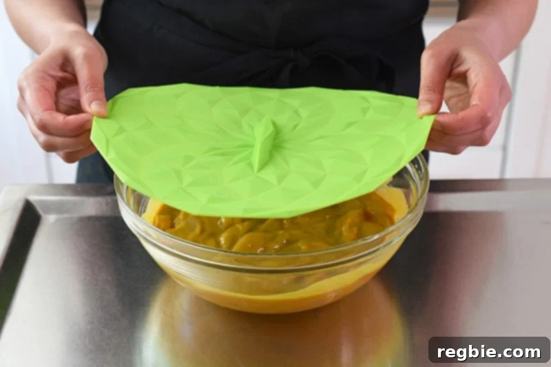 Covering the bowl of marinated chicken with a green silicone lid, signifying the start of the marination process.