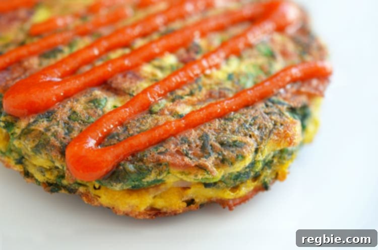 Wholesome Whole30 Keto Egg Foo Young 11 A closeup of gluten-free and paleo Egg Foo Young with a squiggle of Whole30 sriracha on top.