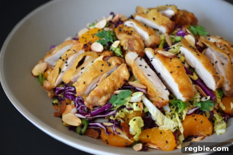 A close up of Whole30-friendly Chinese Chicken Salad, a colorful blend of cabbage, carrots, mandarin oranges, herbs, and crispy Cracklin' Chicken.