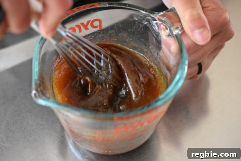 An overhead shot of someone whisking All-Purpose Stir-Fry Sauce with avocado oil to make a Whole30 salad dressing.