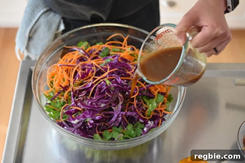 Pouring the paleo salad dressing over the Whole30-friendly Chinese Chicken Salad.