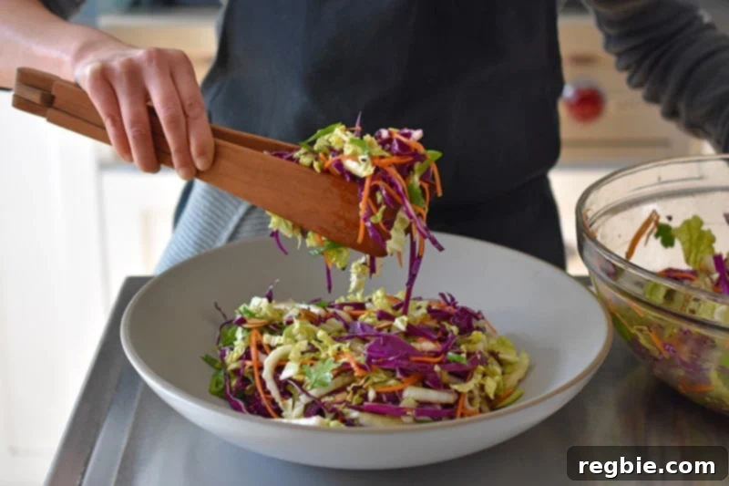 Transferring the Whole30 Chinese Chicken Salad to a large grey ceramic serving platter.