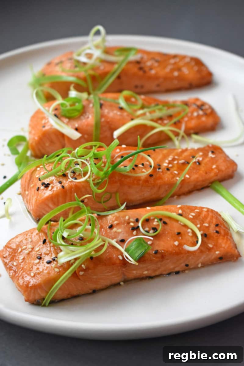 A vibrant platter of perfectly baked Easy Teriyaki Salmon, garnished with sesame seeds and green onions, showcasing a healthy, Whole30, paleo, and gluten-free weeknight dinner option.