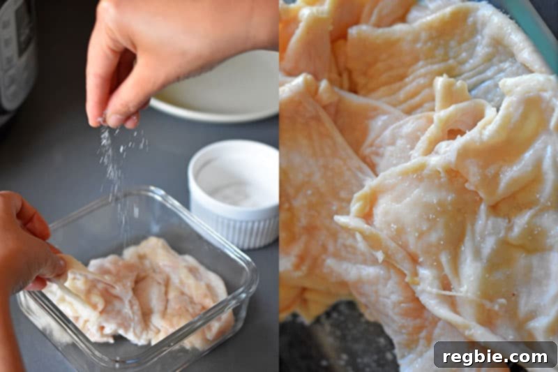 A hand is sprinkling kosher salt on raw chicken skin, preparing it for cooking.