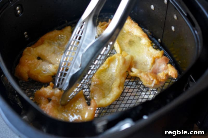 Flipping the chicken skins in an air fryer at the halfway point to ensure even crisping on both sides.