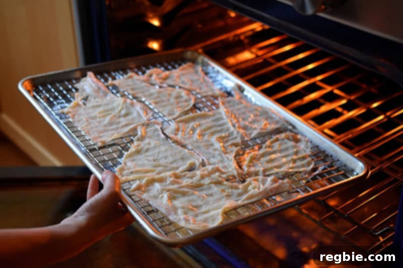 Placing a tray of chicken skins into the oven to make a keto snack, beginning the baking process.