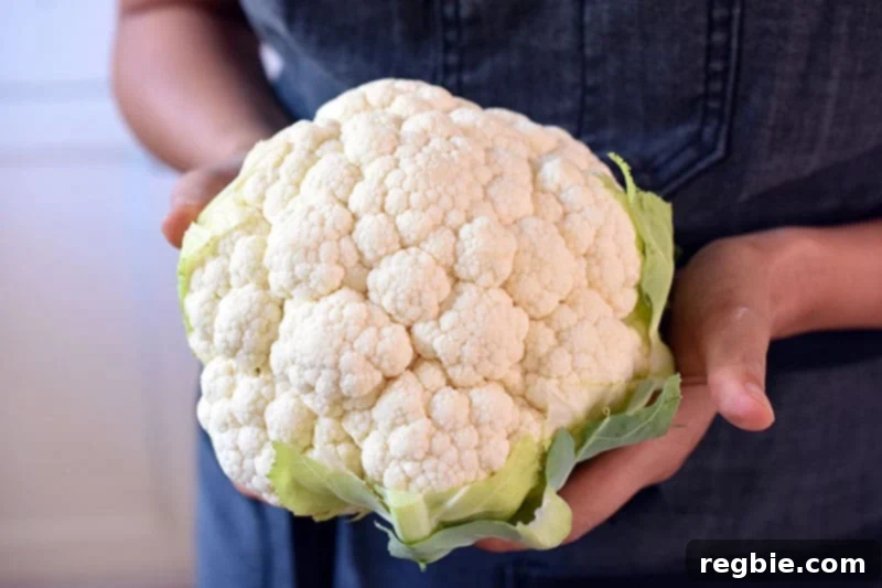 Someone holding a head of cauliflower, ready for preparation to be made into Tandoori Whole Roasted Cauliflower.