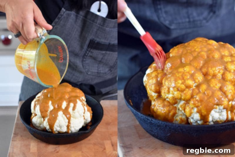 Someone pouring the vibrant Tandoori marinade over the top of a whole cauliflower, ensuring full coverage before roasting.