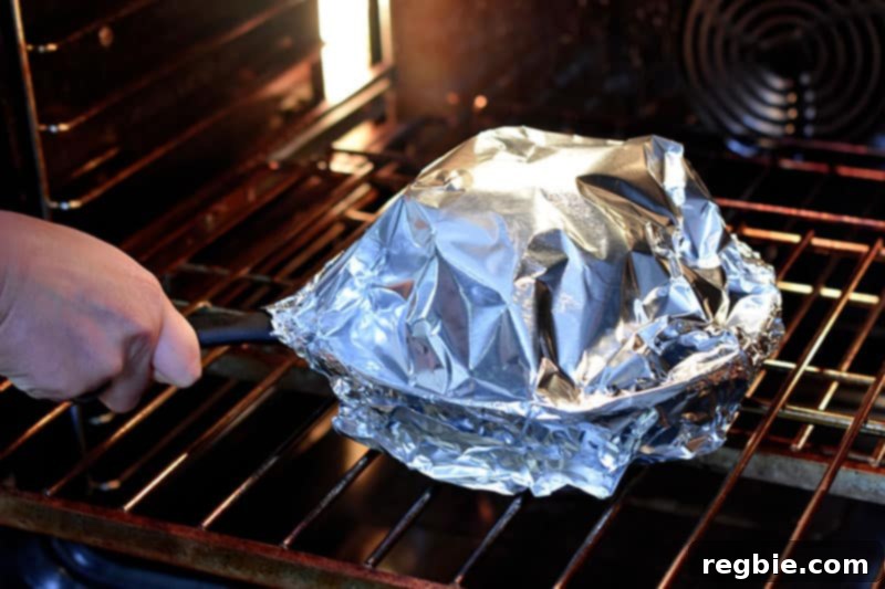 Tandoori Whole Roasted Cauliflower covered with foil, baking in the oven on the middle rack.