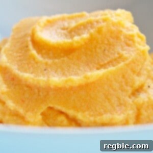 A beautifully presented bowl of creamy cauliflower, carrot, and parsnip puree, garnished with fresh herbs.