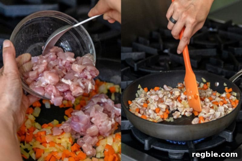 Adding diced raw chicken to a pan with sautéed onions and carrots.