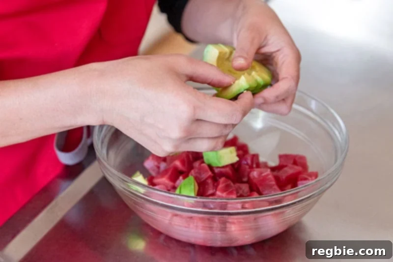 Clean Eating Tuna Avocado Poke 6 Adding creamy diced avocado to the fresh raw tuna cubes in a large bowl, ready for the poke sauce.