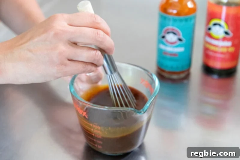 Vigorously whisking together homemade paleo and Whole30 marinades: All-Purpose Stir-Fry Sauce and Whole30 Sriracha, for Chinese Chicken Wings.