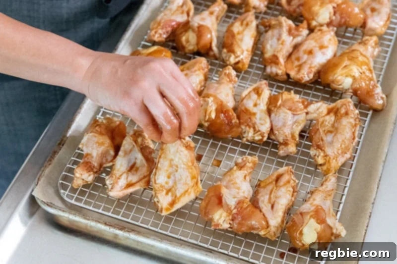 Carefully placing Whole30 Chinese Chicken Wings in a single layer on a wire rack set over a lined rimmed baking sheet, ready for oven roasting.