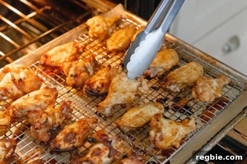 Flipping perfectly browned paleo, Whole30, and gluten-free Chinese Chicken Wings on a rack to achieve even cooking and crispiness in the oven.