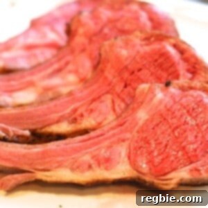 A rack of lamb cut into it's chops laying on a white plate.