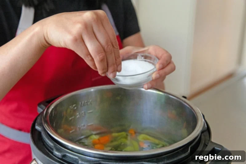 Someone adds a pinch of Diamond Crystal kosher salt to the Instant Pot Vegetable Soup, perfecting the seasoning.