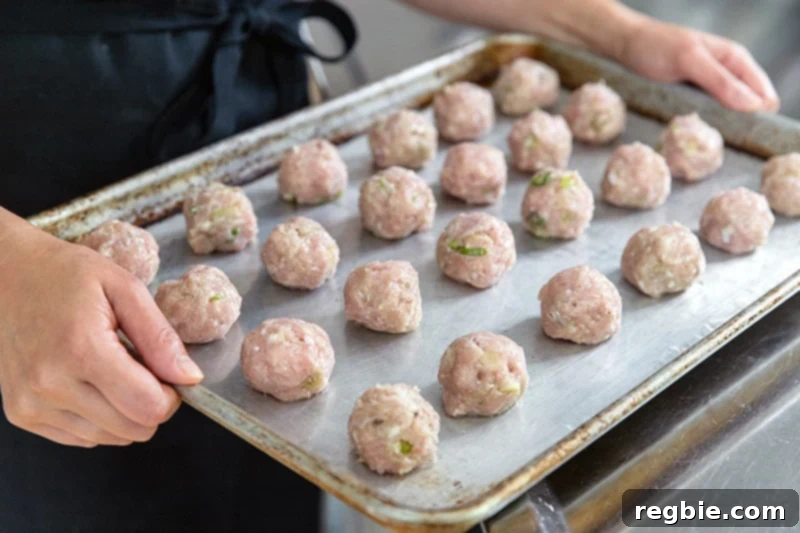 A rimmed baking sheet filled with Whole30 tsukune meatballs, perfectly arranged and ready for the oven.