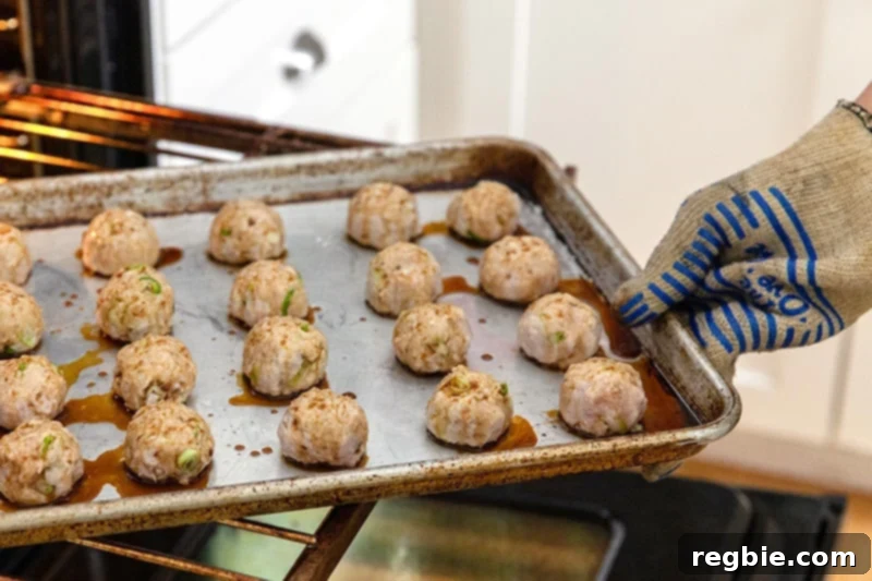 Rotating a tray of Whole30 tsukune, Japanese ground chicken meatballs, in the oven during the broiling process.
