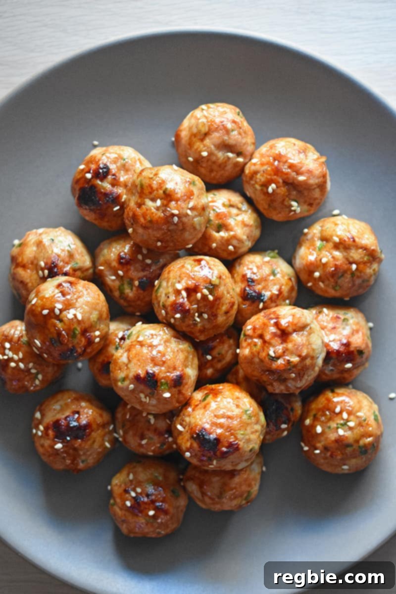 A platter piled high with Whole30-friendly tsukune, Japanese chicken meatballs, garnished with sesame seeds.