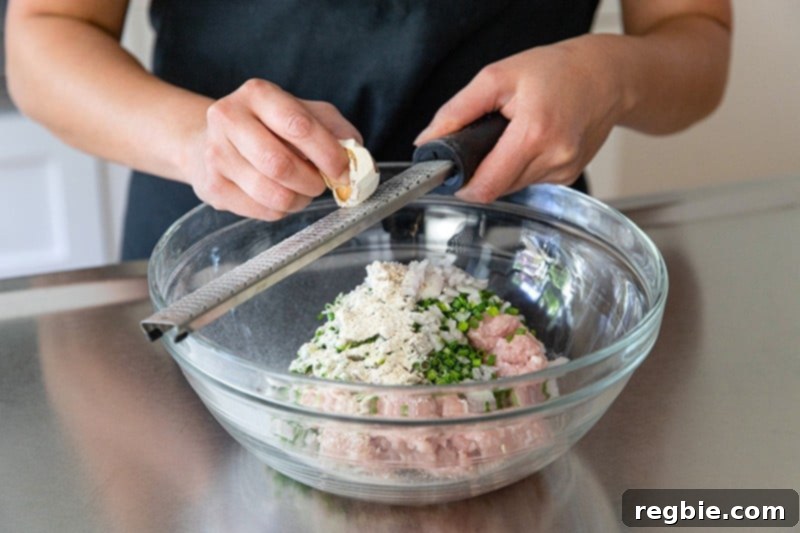Grating a dried shiitake mushroom onto the paleo tsukune meatball mixture using a microplane.