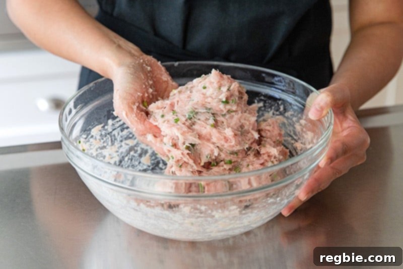 Kneading the paleo tsukune ground chicken mixture until it becomes sticky and tacky in texture.