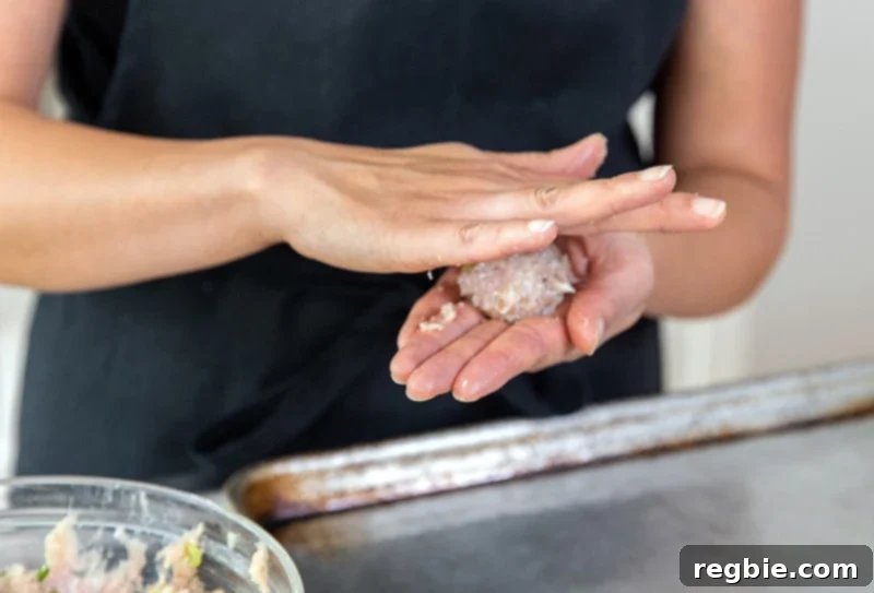 Rolling the tsukune meatballs by hand into uniform balls on a clean surface.