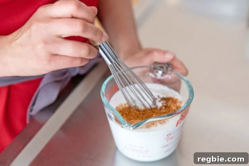 Whisking together coconut milk and tandoori spices in a measuring cup to make keto Sheet Pan Tandoori Chicken