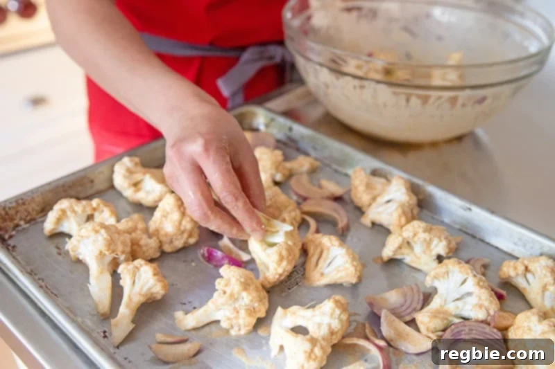 Arranging tandoori-marinated cauliflower and onions on a sheet pan.