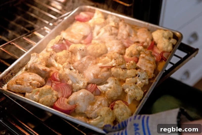 Rotating paleo sheet pan chicken tandoori at the halfway point in the oven. 