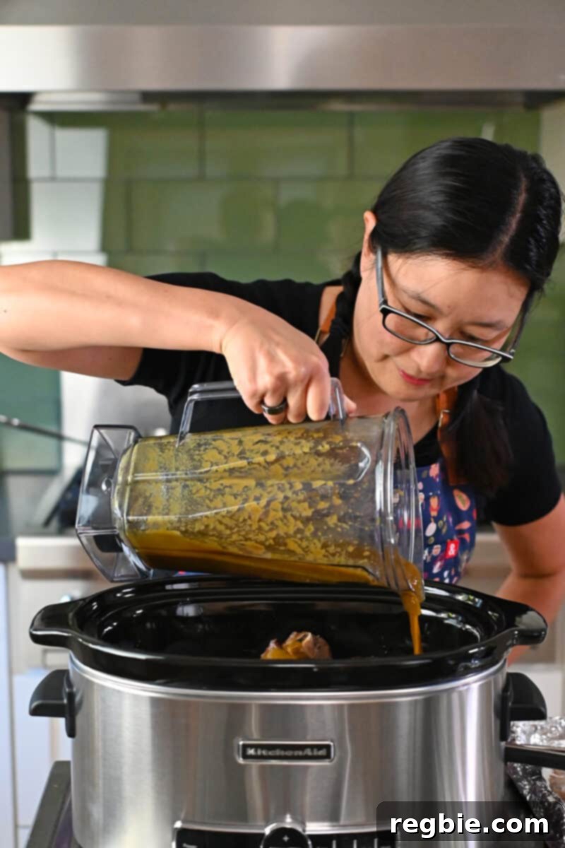 Fall-Off-The-Bone Slow Cooker Korean Short Ribs 12 An Asian woman in glasses is pouring a brown sauce into an open slow cooker.
