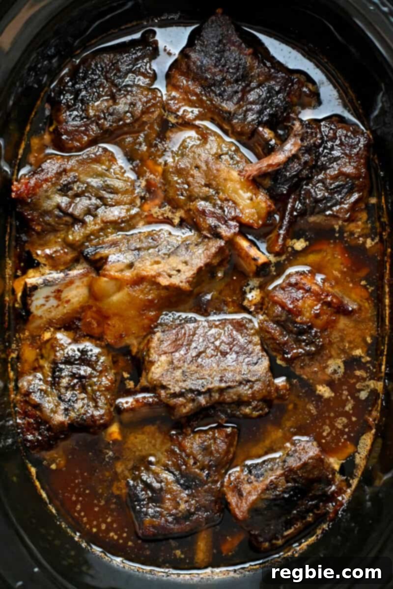 Fall-Off-The-Bone Slow Cooker Korean Short Ribs 14 An open slow cooker filled with braised Korean Short Ribs that are ready to serve.