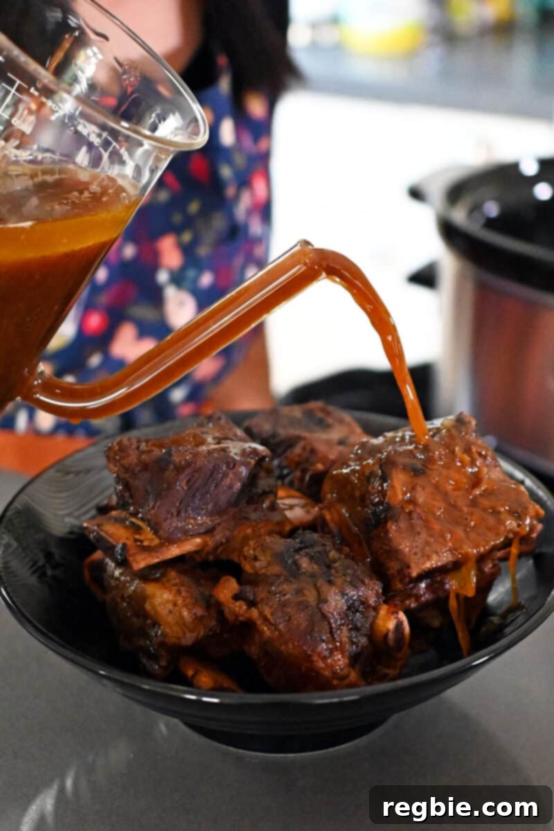 Fall-Off-The-Bone Slow Cooker Korean Short Ribs 16 Pouring sauce from a fat separator onto a platter of braised Korean short ribs,
