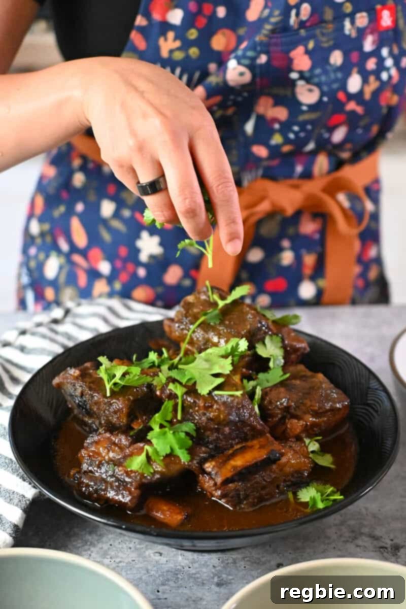 Fall-Off-The-Bone Slow Cooker Korean Short Ribs 17 Adding chopped cilantro to a platter of braised slow cooker Korean Short Ribs
