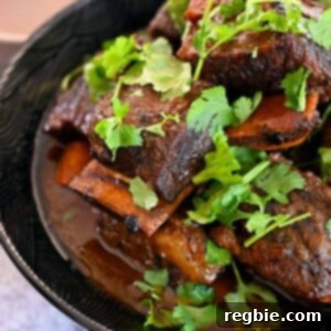 An bowl filled with braised Korean Short Ribs topped with cilantro in a black bowl.