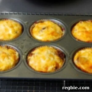 A tray of six mini frittata muffins with cheese and beef, ready to eat.
