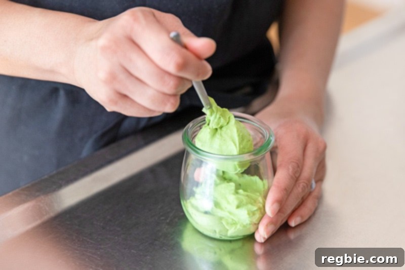 Creamy Paleo Dairy Free Matcha Pudding 12 A serving spoon gracefully scooping creamy matcha pudding into a clear glass, showcasing its smooth texture and vibrant green hue.
